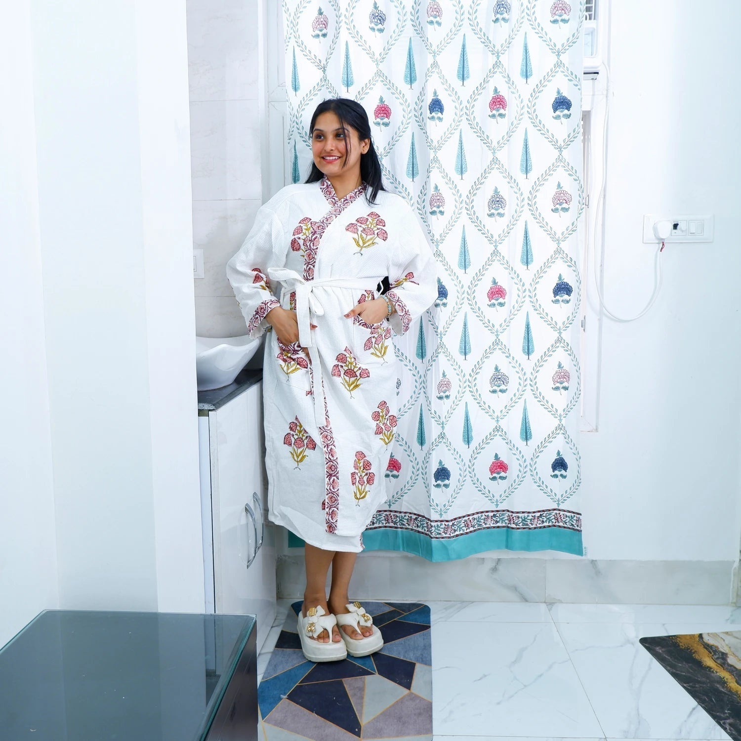 Woman in a hand block printed cotton bathrobe with floral designs, standing in a modern bathroom