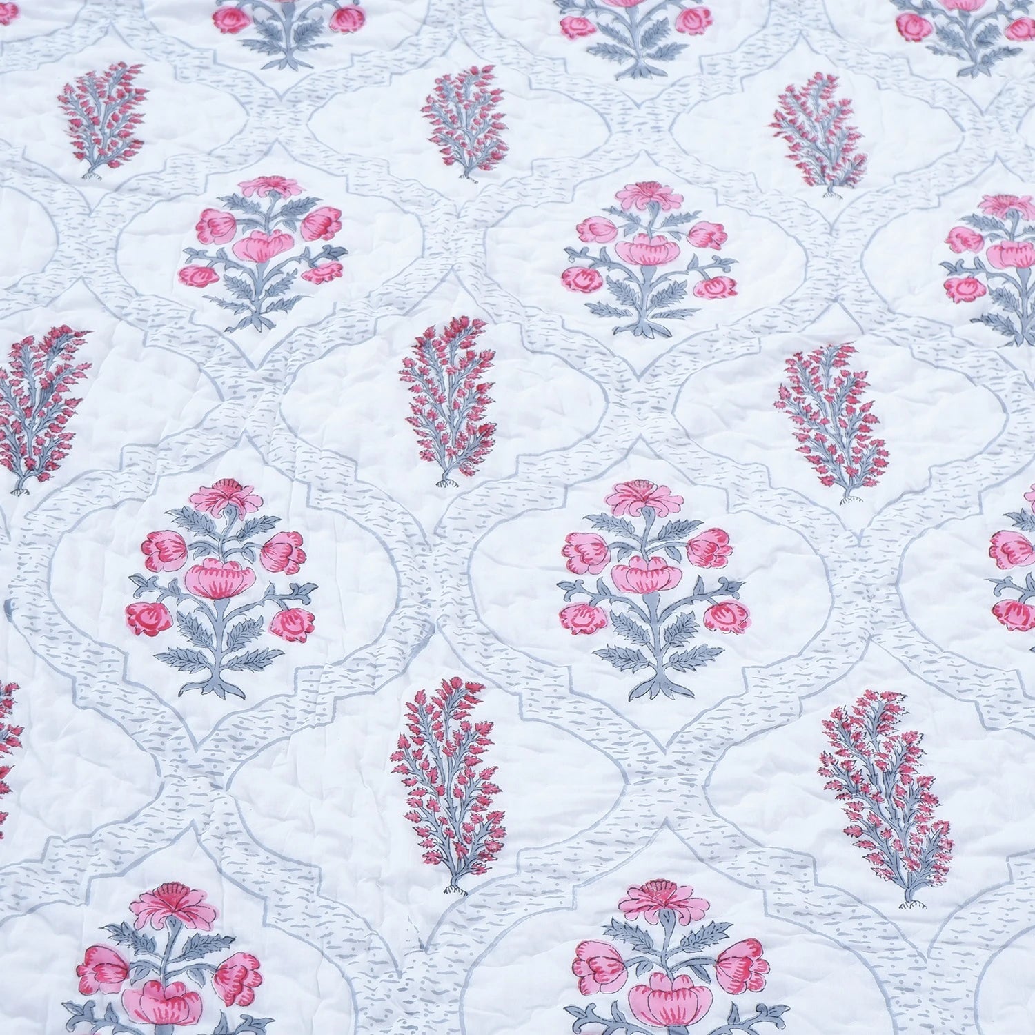 Handcrafted Jaipur quilts for bedroom featuring floral patterns in pink and gray on a white background