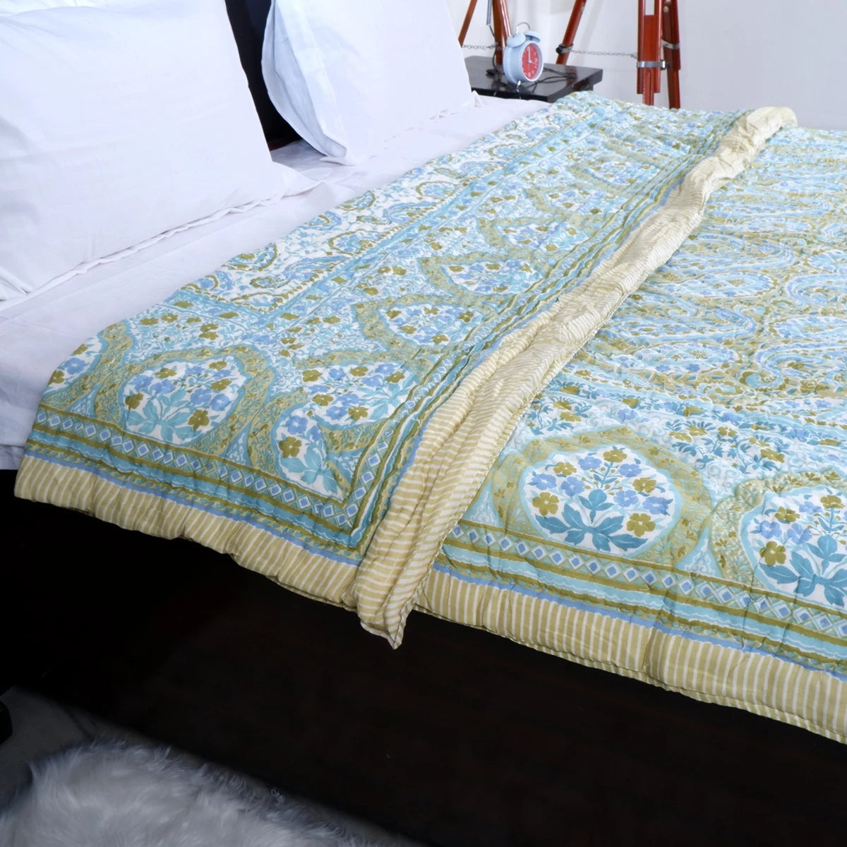 Jaipuri block print comforter for winter in blue and green design on bed with white linens