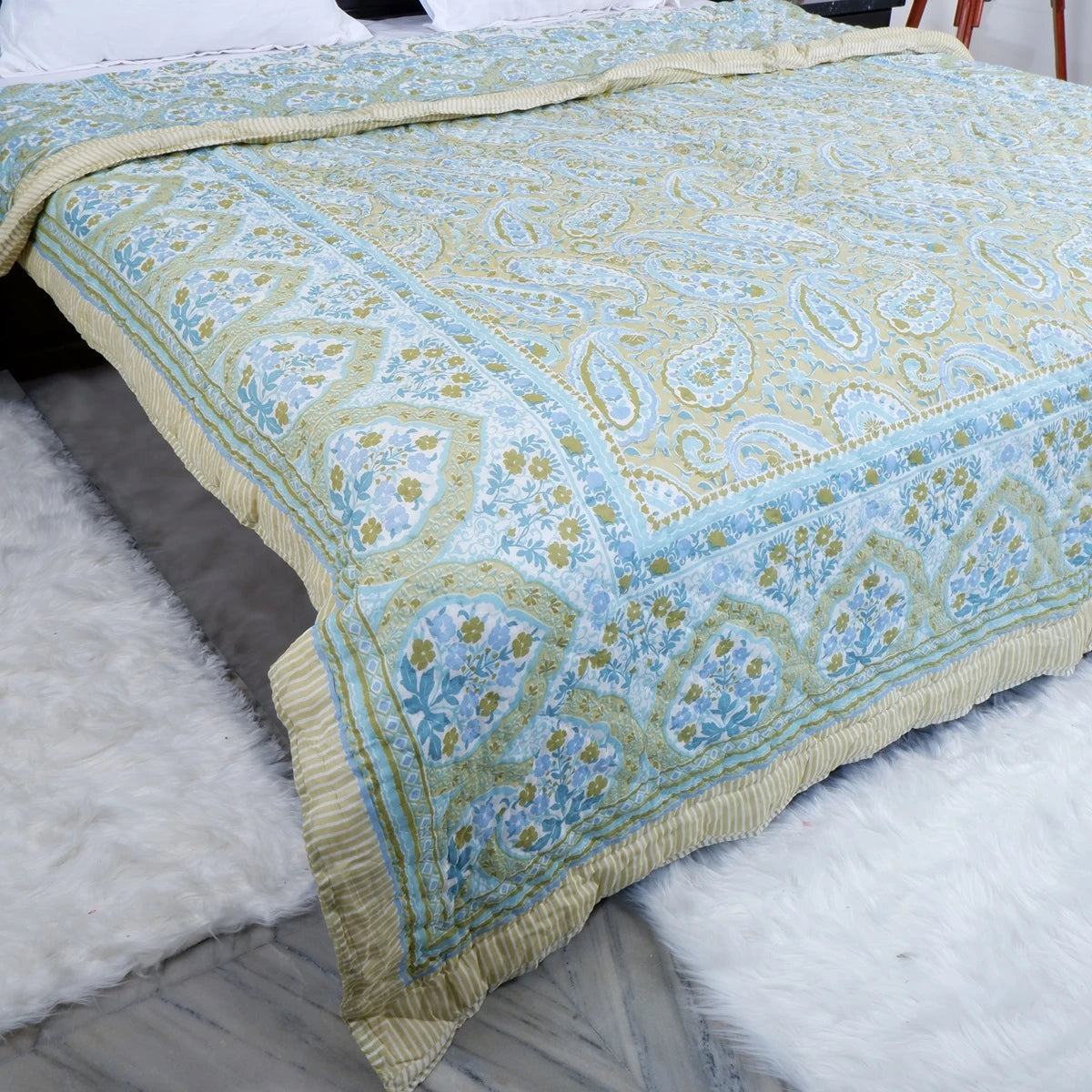 Jaipuri block print comforter for winter in light blue and green floral design on a cozy bed