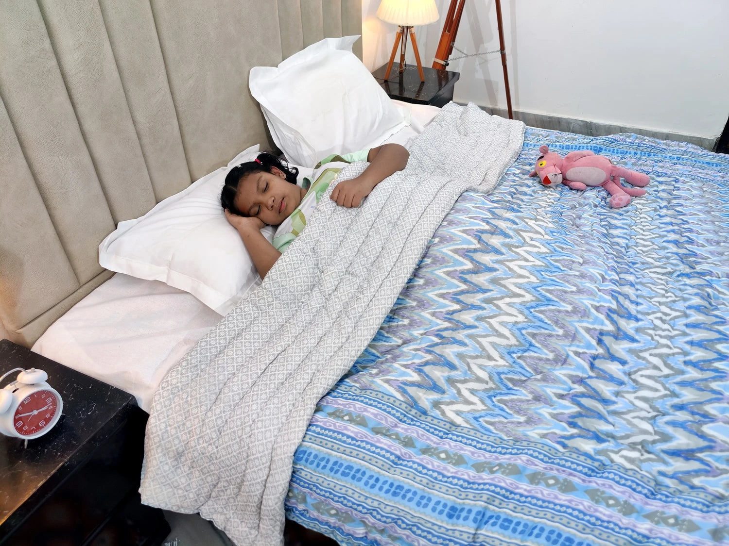 Child sleeping comfortably under a Jaipuri cotton quilt double bed with vibrant patterns and cozy design