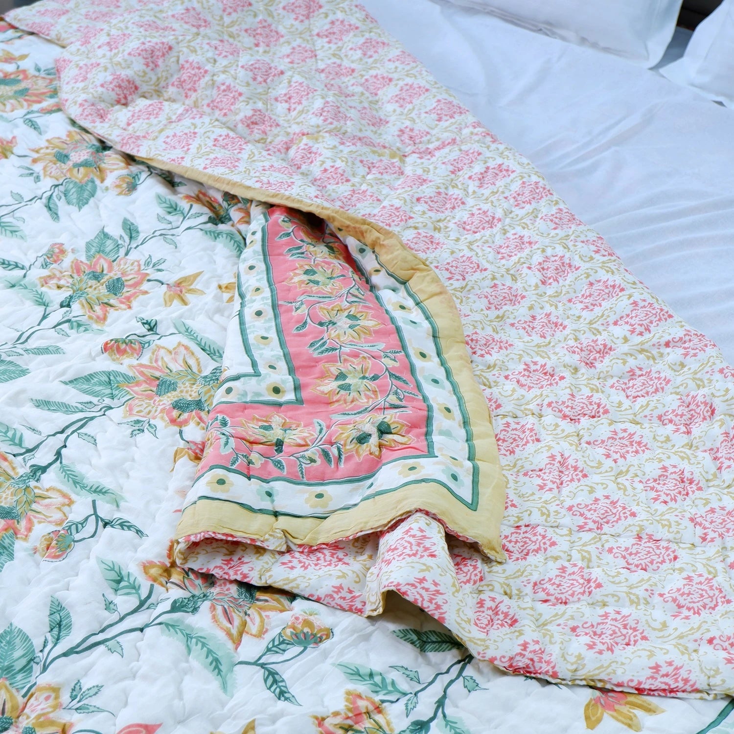 Jaipuri cotton quilt double bed with floral patterns and vibrant colors on a white bedspread