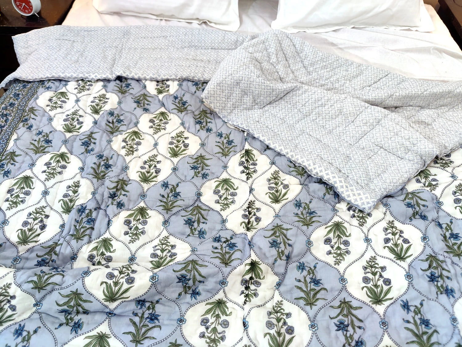 Jaipuri cotton quilt double bed featuring a floral pattern in blue and green tones elegantly draped on a bed