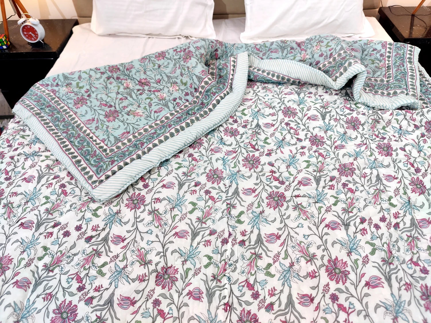Jaipuri cotton quilt double bed with floral patterns and intricate border design on a bed