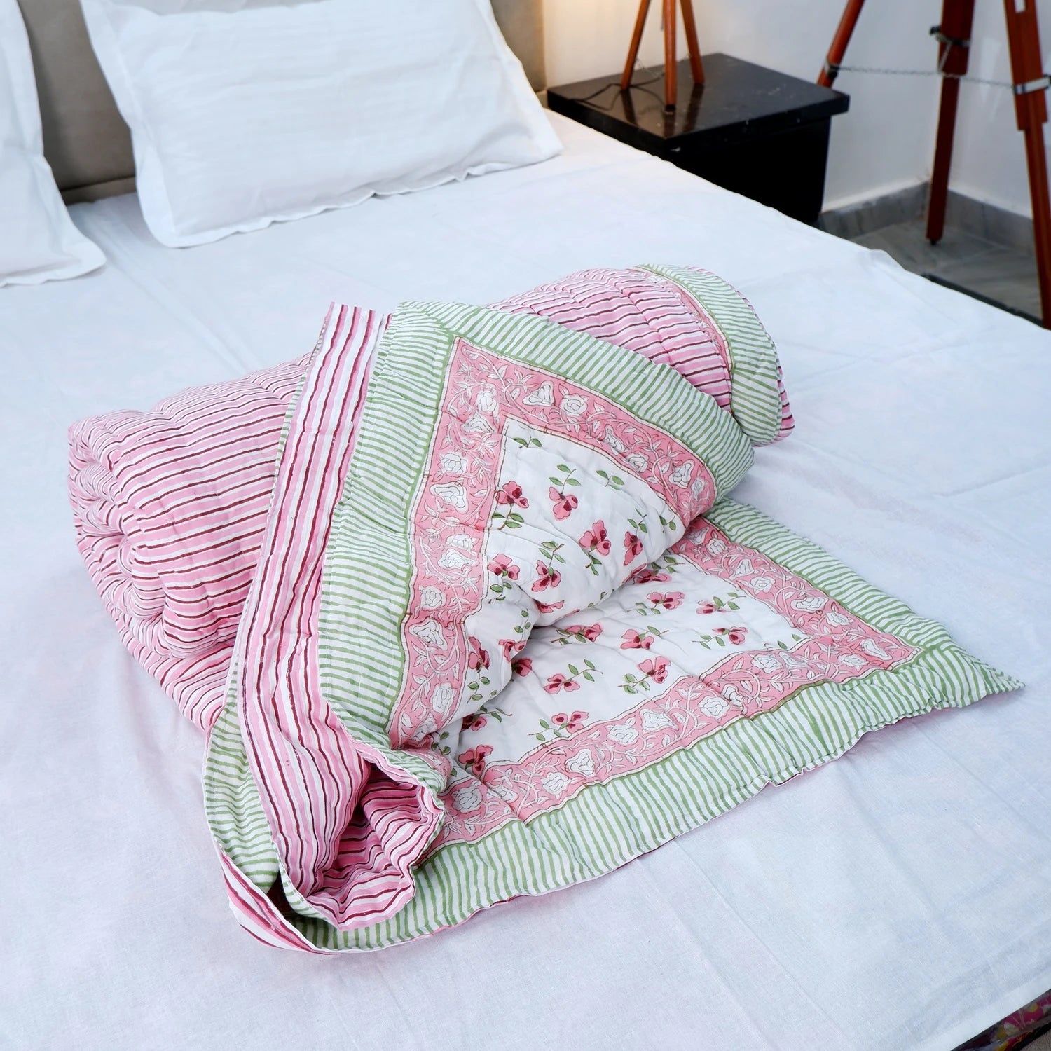 Jaipuri cotton quilt double bed in pink and green floral design, elegantly draped on a white bed