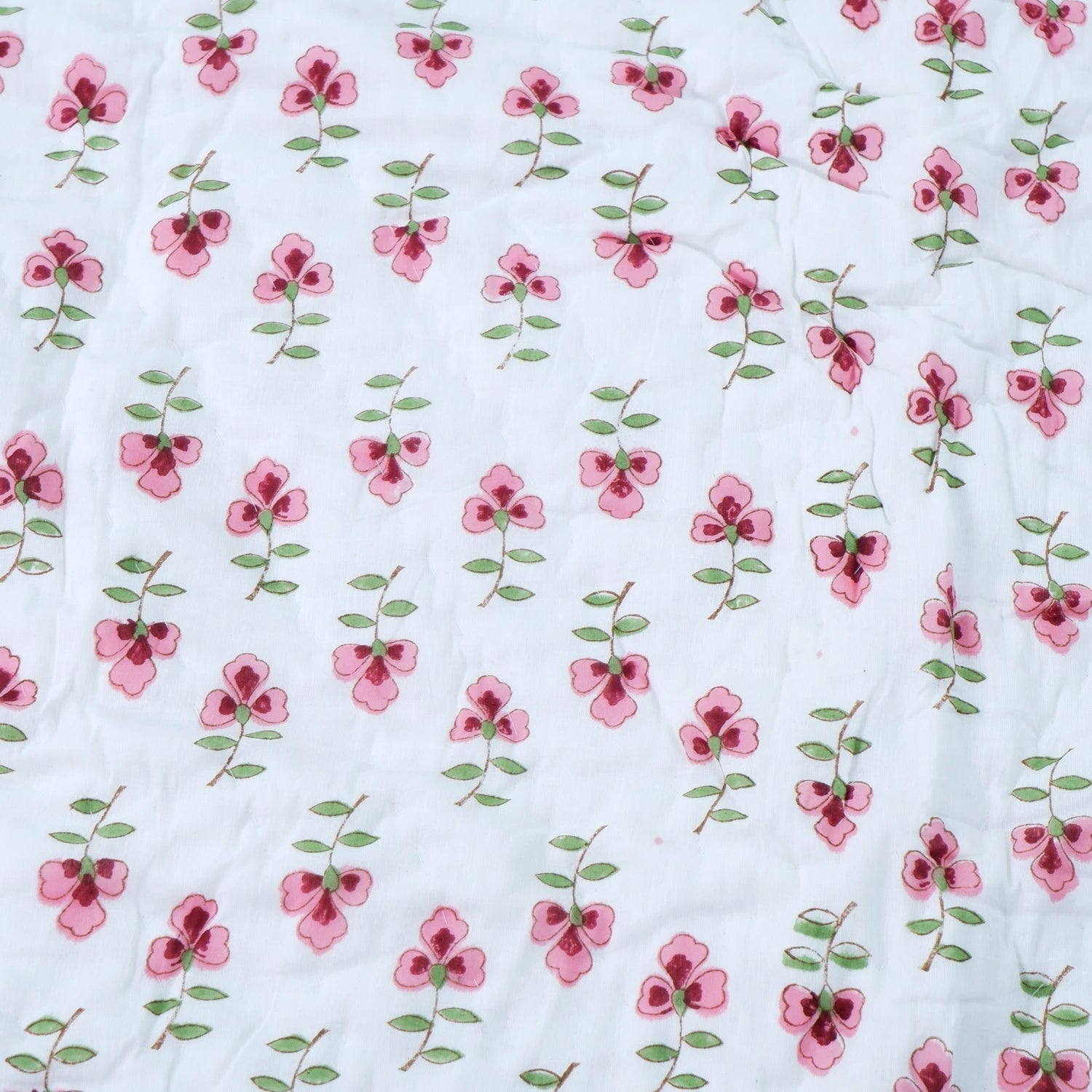 Jaipuri cotton quilt double bed with floral design in pink and green on a white background
