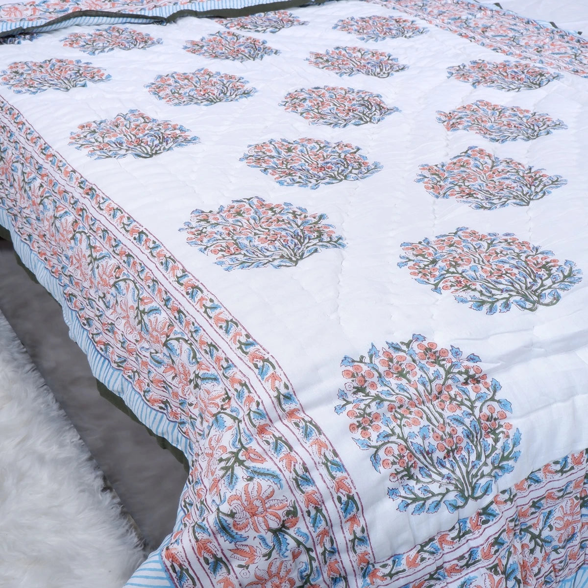 Jaipuri cotton quilt single bed with intricate floral patterns in soft pastel colors and hand-stitched details.