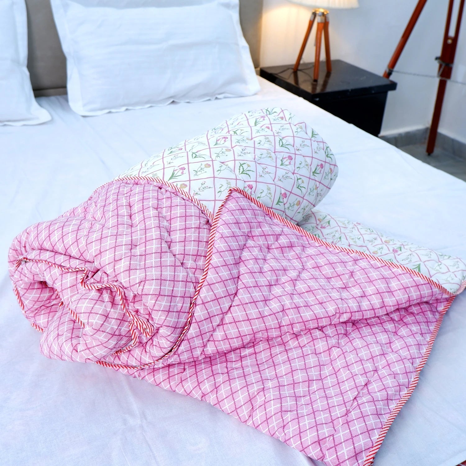 Jaipuri cotton quilts double bed in pink and green floral patterns folded on a white bed