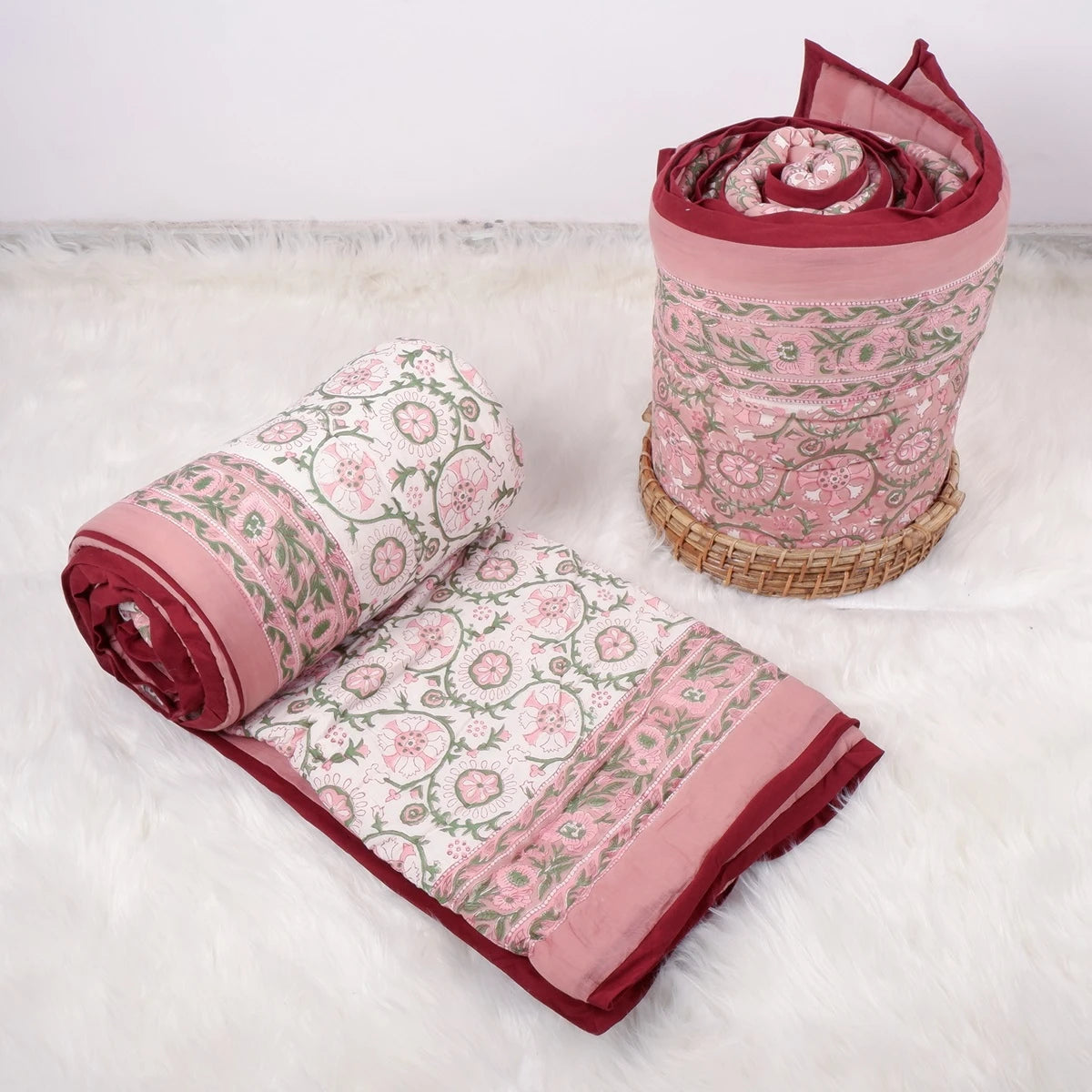 Jaipuri pure cotton quilt single bed in pink floral design, rolled and laid flat on a soft surface