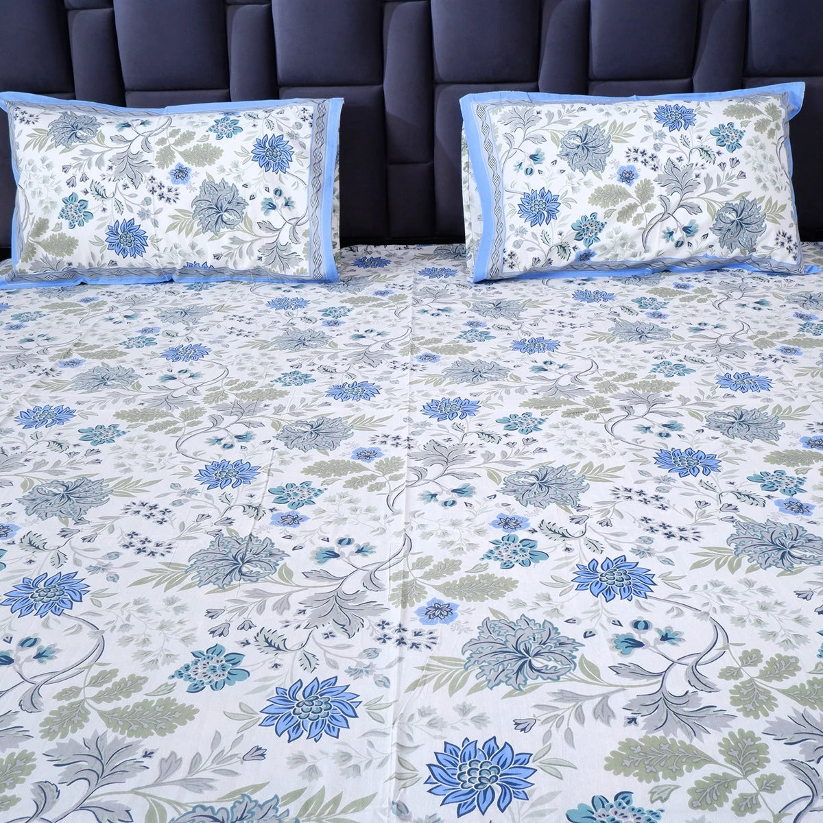 The Jaipuri pure cotton bed sheet set featuring floral patterns in blue and green on a white background